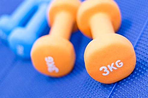 A pair of orange dumb-bells – part of a product photography commission at Allendale Forge.