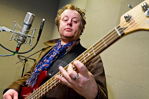 A man playing a guitar in the sound studio at Allendale Forge in Northumberland. 