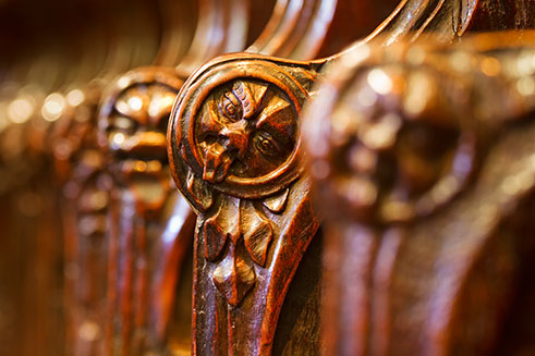 A close-up photograph of mischievously-carved choir stalls in Hexham Abbey, Northumberland. 