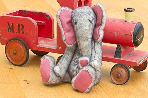 A cuddly toy elephant beside a wooden toy train, part of a commission for Emily’s Ark. 
