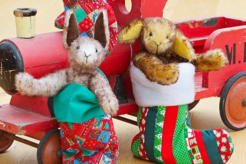 A cute image of two hand-crafted animals by Emily’s Ark, sitting in Christmas stockings.