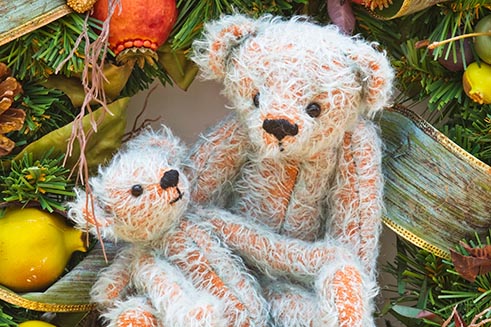 Two hand-made bears sitting amongst Christmas decorations, part of a marketing project for Emily’s Ark. 