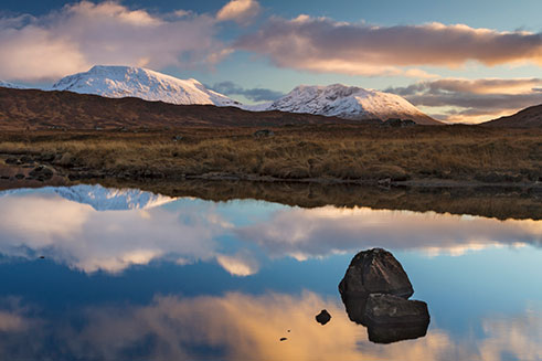 Image of a sunset over the Scottish Highlands in winter, with snow on the mountains. 